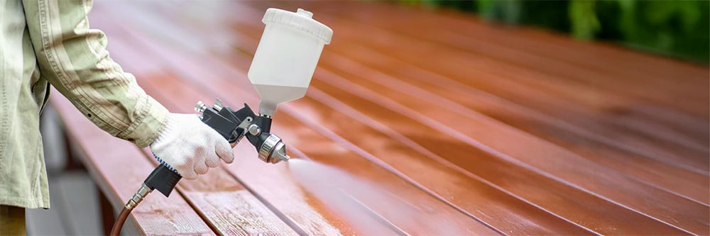 Holzoberfläche wird mit einer Druckluft-Lackierpistole gleichmäßig lackiert